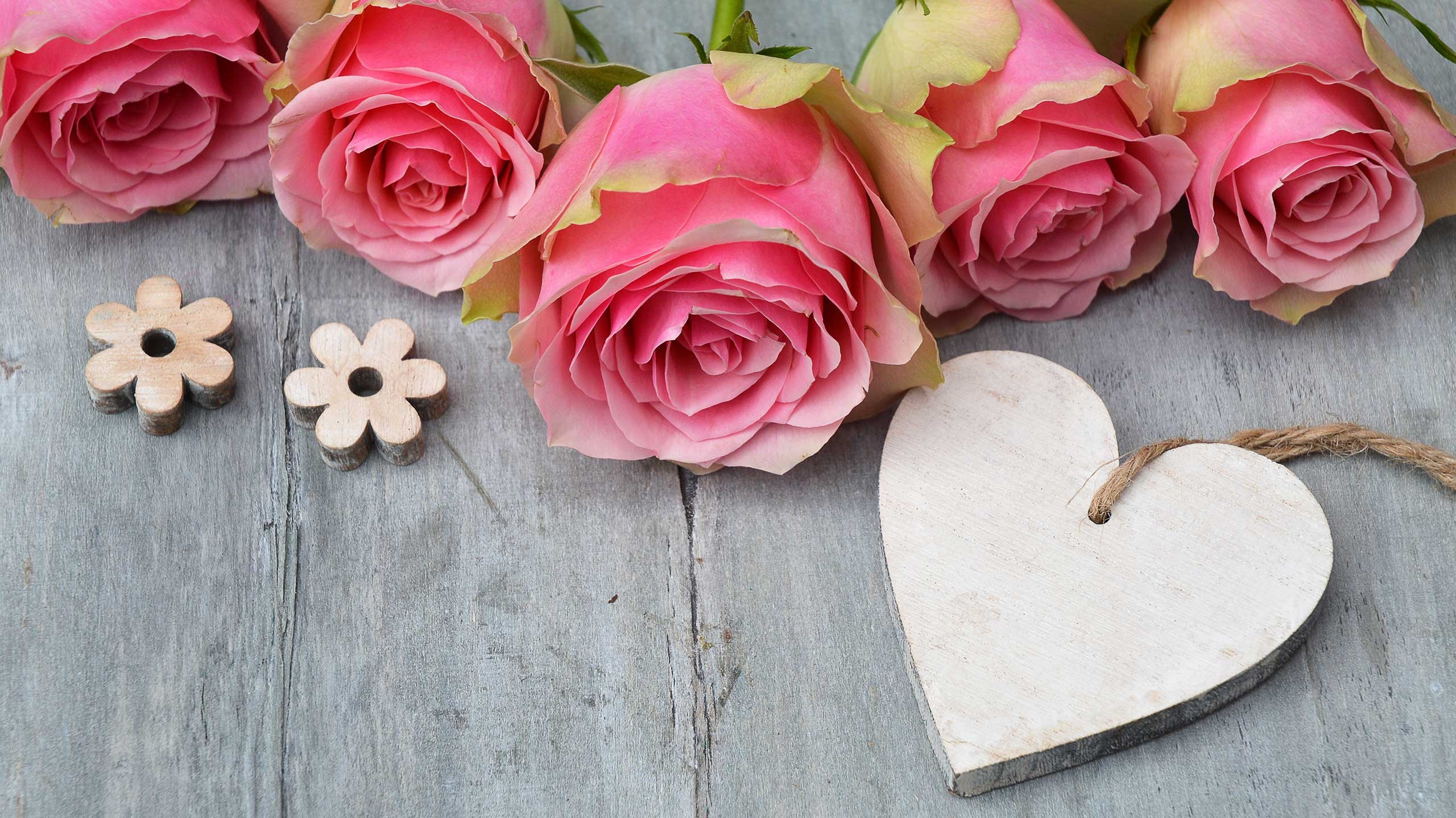 Valentinstag Herz aus Holz mit rosa Rosen auf Holztisch